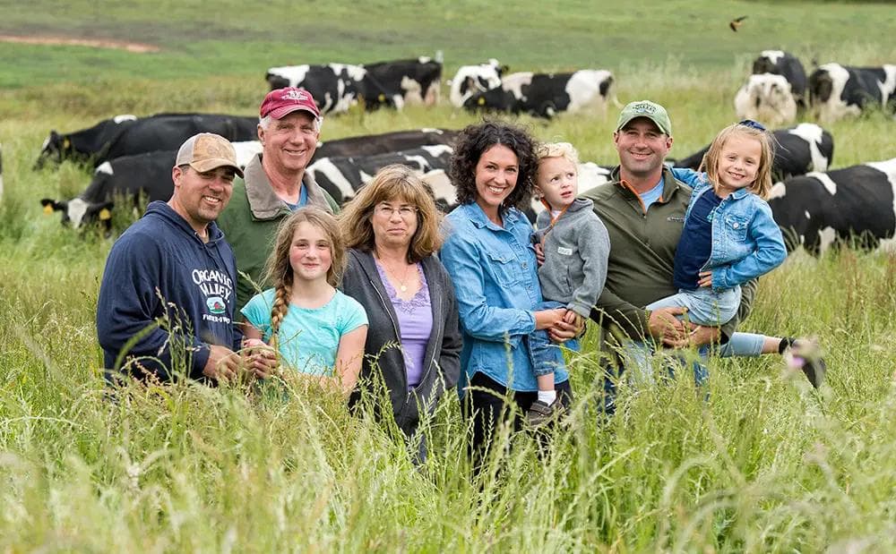 An Organic Valley farm family standing in the pasture with cows in the background
